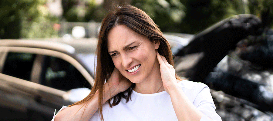 Woman with whiplash standing outside of her car after a car accident in Tulsa, OK